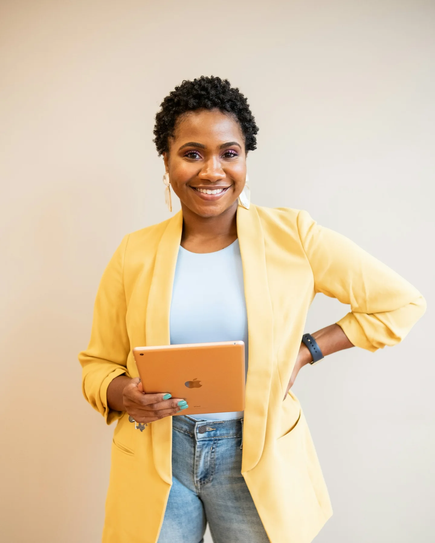 Profissional sorridente usando blazer amarelo e segurando um tablet
